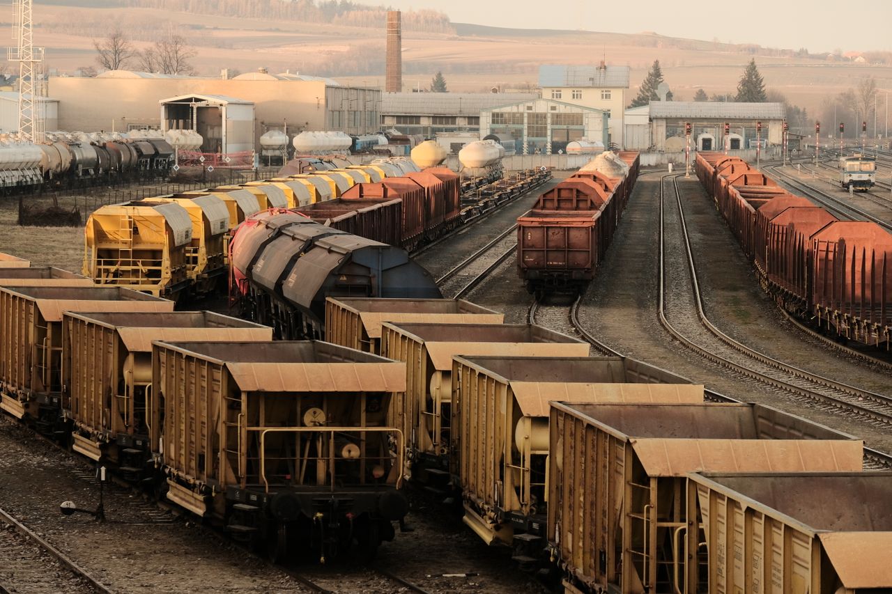 The Art of Drawing Readers In: Your attractive post title goes here A busy freight train yard with multiple tracks and a variety of train cars in a rural setting.